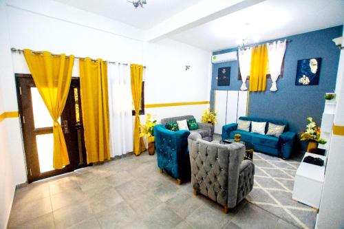 a living room with two blue couches and yellow curtains at Appartement meublé in Douala