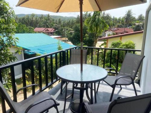 a table and chairs on a balcony with an umbrella at S&S House in Srithanu