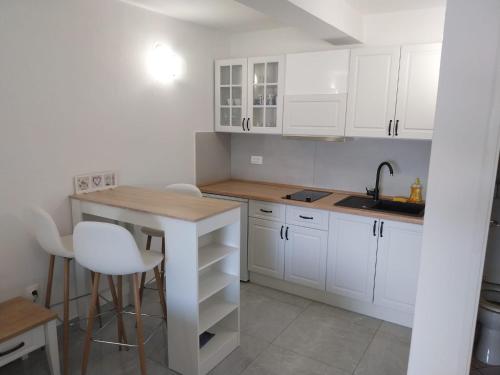 uma cozinha com armários brancos, uma mesa e um lavatório em Apartments Lumbarda em Lumbarda