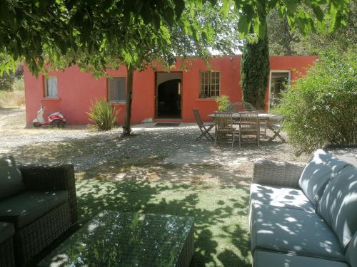 ein rotes Haus mit einem Tisch und Stühlen im Hof in der Unterkunft Hacienda, villaT4 de 110m2 proche de St Florent in Patrimonio
