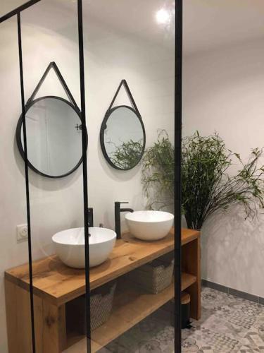 une salle de bain avec deux lavabos et deux miroirs dans l'établissement Appartement chaleureux aux portes de Bordeaux, à Macau