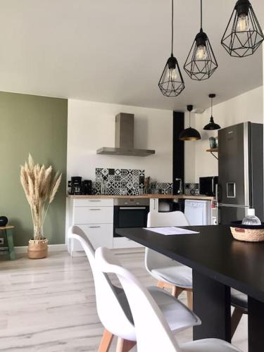 une cuisine avec une table noire et des chaises blanches dans l'établissement Appartement chaleureux aux portes de Bordeaux, à Macau