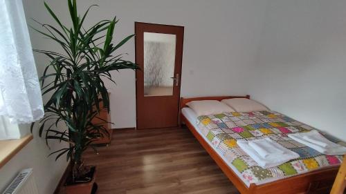 - une chambre avec un lit et une plante en pot dans l'établissement Apartmán AMSEL, à Ostrov