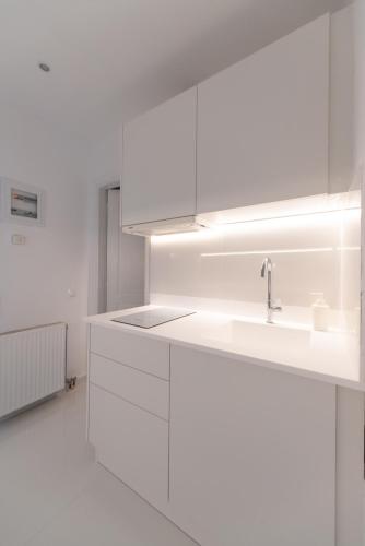 a white kitchen with white cabinets and a sink at Aeri Villas & Apartments in Tourlos