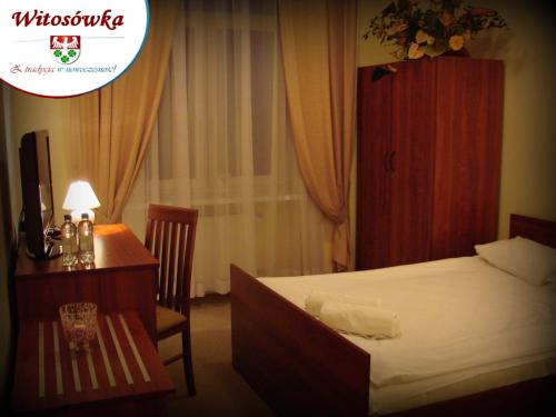 um quarto de hotel com uma cama, uma secretária e uma mesa em Pokoje Gościnne w Centrum Kultury Wsi Polskiej em Wierzchoslawice