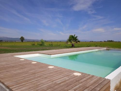 einen Pool mit einer Holzterrasse neben einem Feld in der Unterkunft MAS CATXINA Hotel Boutique 4 estrellas in Deltebre