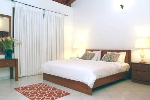 1 dormitorio con 1 cama con sábanas blancas y espejo en Luxury Colombo Escape, en Talawatugoda