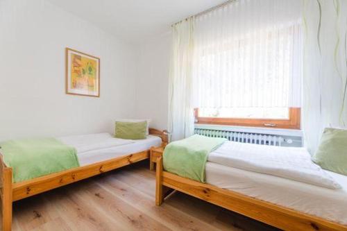 2 Einzelbetten in einem Zimmer mit Fenster in der Unterkunft Haus am Sonnenhang Typ B in Niedersalwey