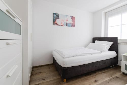 a small bedroom with a bed with white sheets and a window at Haus Salweyblick in Niedersalwey