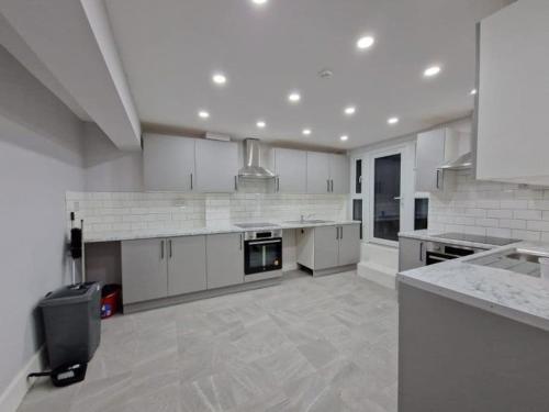 a large kitchen with white cabinets and appliances at Hackney Spacious En-Suite in London