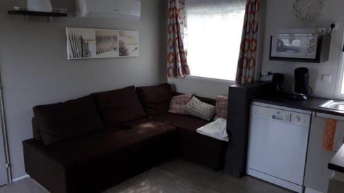 un salon avec un canapé marron et une cuisine dans l'établissement Mobil Home 3 Chambres - 2 salles d'eau - 2WC -Camping Les Ecureuils Biscarrosse lac - 220 Euro à régler à l'accueil, à Biscarrosse