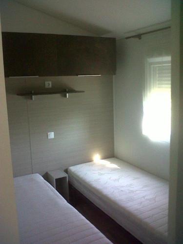 Cette chambre comprend deux lits et une fenêtre lumineuse. dans l'établissement Mobil Home 3 Chambres - 2 salles d'eau - 2WC -Camping Les Ecureuils Biscarrosse lac - 220 Euro à régler à l'accueil, à Biscarrosse