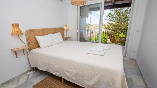 a bedroom with a bed and a large window at Jardines de la Duquesa 26 in Manilva