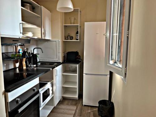 une cuisine avec des armoires blanches et un réfrigérateur blanc dans l'établissement The Garden YourHostHelper, à Villejuif