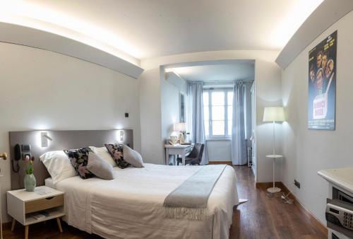 una camera bianca con un grande letto e una scrivania di Locanda agli Amici a Cortona