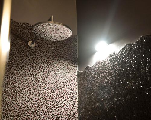 a bathroom with a shower and a wall with a light at PARADISE RANCH in Borgo Sabotino