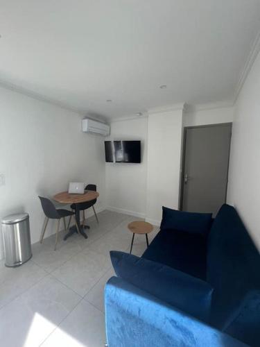 a living room with a blue couch and a table at Appt 1 chambre jardin parking in Narbonne