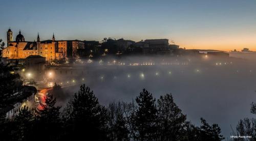 a foggy view of a city at night with lights at Hotel Mamiani & Relaxing Spa Urbino in Urbino