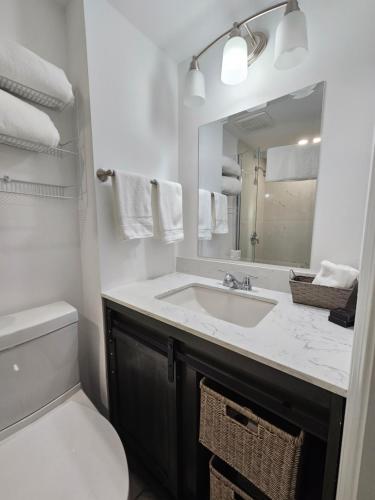 W łazience znajduje się umywalka, toaleta i lustro. w obiekcie Sunflower Guest Suites w mieście Summerside