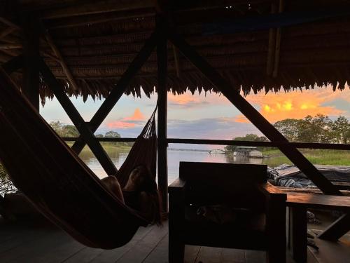 a person sleeping in a hammock in front of a river at Cabaña Flotante Kurupira in Leticia