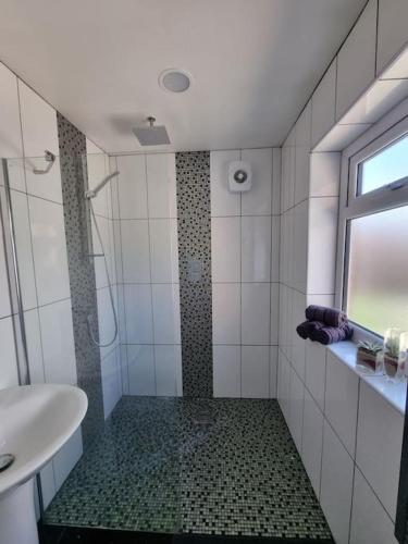 baño con ducha, lavabo y ventana en Somers Lodge en Leicester