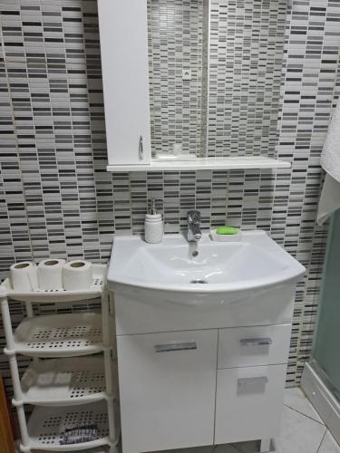 een badkamer met een witte wastafel en een spiegel bij Enjoy traveling in Tuzla