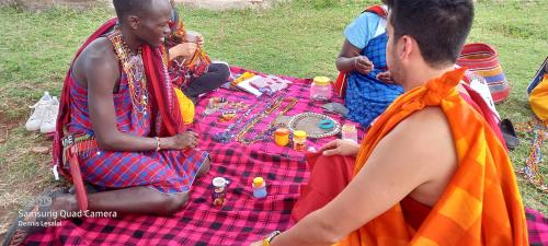 a group of people sitting on a picnic blanket at Orboma Masai homestay in Sekenani