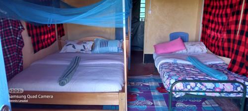 a couple of beds in a room with a bunk bed at Orboma Masai homestay in Sekenani