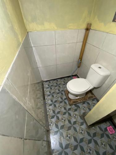 a bathroom with a toilet and a tiled floor at D'Yoga Bamboo House in Kintamani