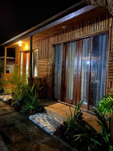 a house with wooden doors and windows at night at D'Yoga Bamboo House in Kintamani