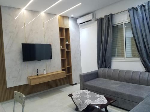 a living room with a couch and a flat screen tv at Joli Villa à Sahloul in Sousse