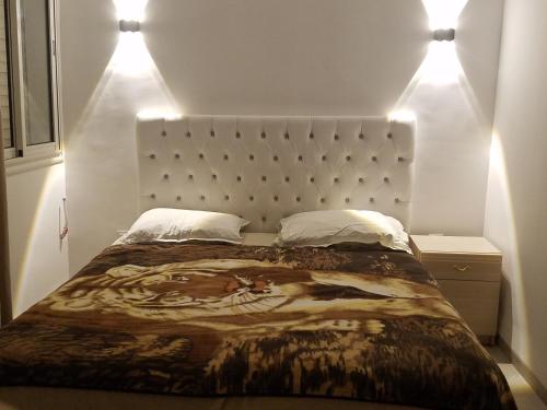 a bedroom with a large bed with two lights on it at Joli Villa à Sahloul in Sousse