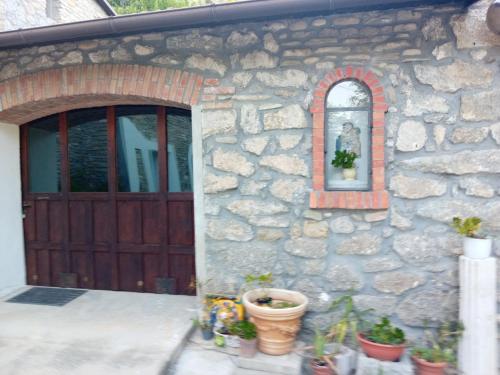 a stone house with a wooden door and potted plants at B&B BORGORI' in Rivola