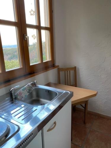 - une cuisine avec évier, table et fenêtres dans l'établissement Ferienwohnung „Am Bankzeitweg“, à Saalfeld
