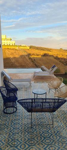 two chairs and tables on a patio with a view at Très belle villa avec piscine et vue incroyable sur mediterannée (DAR NAIM) in Tangier