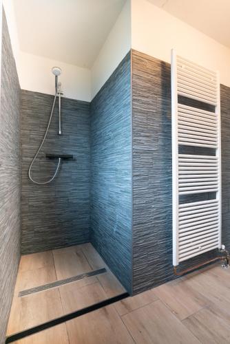 a bathroom with a shower with blue tiles at Goldenescape 6P Vip cottage met royale tuin en Hottub in Ewijk
