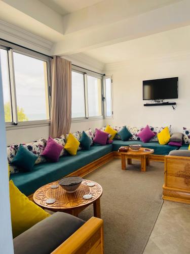 uma sala de estar com um sofá azul com almofadas coloridas em Chez abdelilah em Oualidia