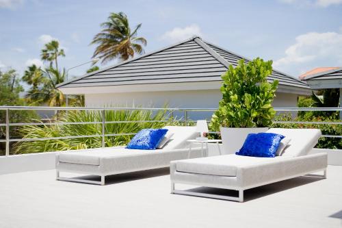 two white chairs and blue pillows on a balcony at Tropical Eden Villa in Jan Thiel