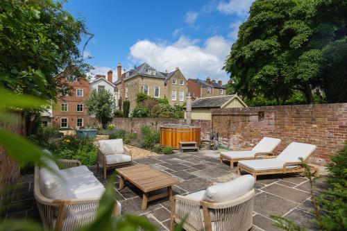 a patio with chairs and tables and a brick wall at Ludlow Townhouse in Ludlow