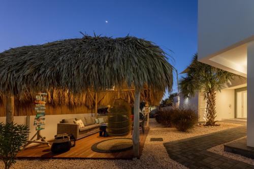 a living room with a couch and a straw umbrella at Tropical Eden Villa in Jan Thiel
