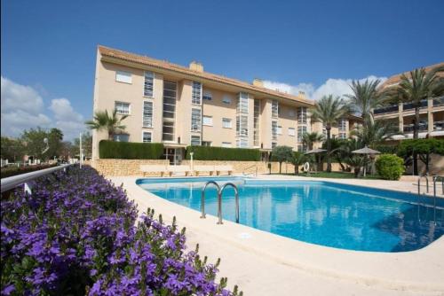 einem Pool vor einem Gebäude mit lila Blumen in der Unterkunft Golden in Jávea