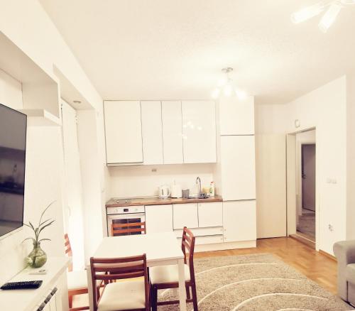 a kitchen with white cabinets and a table and chairs at Central apartment in Prilep in Prilep