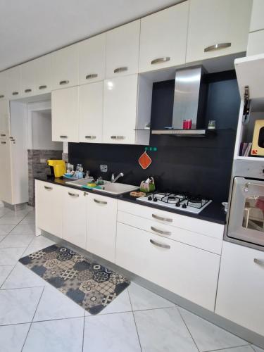 a kitchen with white cabinets and a stove top oven at Appartamento sofí in Fiumicino