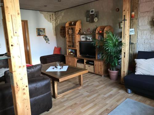 een woonkamer met een tafel en een televisie bij Ferienwohnung-Willgeroth in Ilsenburg