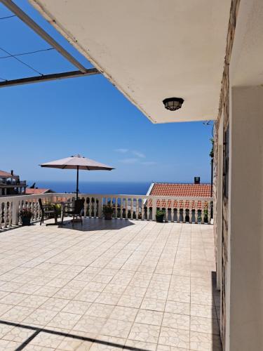 a patio with an umbrella and the ocean in the background at Apartments Dragišić in Sveti Stefan