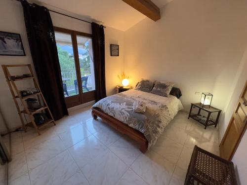 um quarto com uma cama e uma grande janela em Chambre privée avec salle d’eau et terrasse au calme em Le Cannet