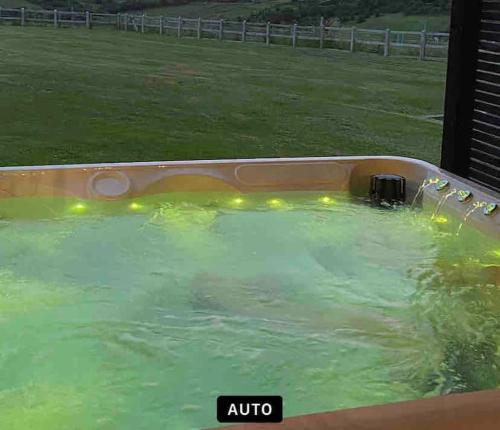 The Stables في Compton Dando: حوض استحمام ساخن بمياه خضراء في حقل