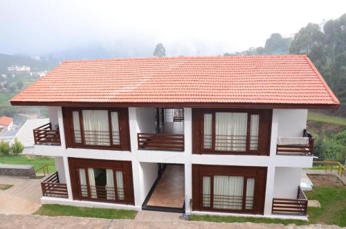 a house with a red roof with a view at GReaT Trails Kodaikanal by GRT Hotels in Kodaikānāl