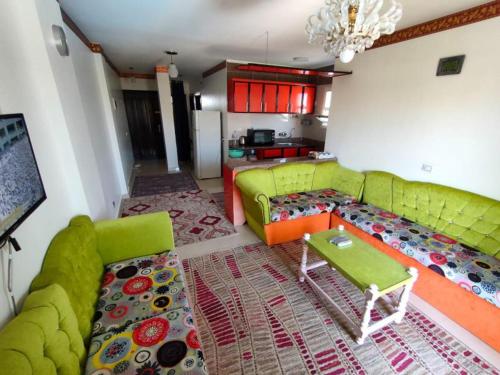 sala de estar con sofá verde y cocina en حجز شاليه غرفتين ورسيبشن بمارينا دلتا, en Al Ḩammād
