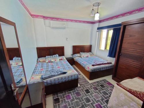 Habitación pequeña con 2 camas y espejo. en حجز شاليه غرفتين ورسيبشن بمارينا دلتا, en Al Ḩammād